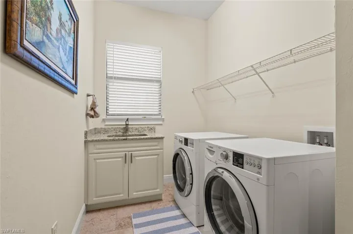 Laundry room featuring washing machine and dryer, light stone finish floors, and cabinet space