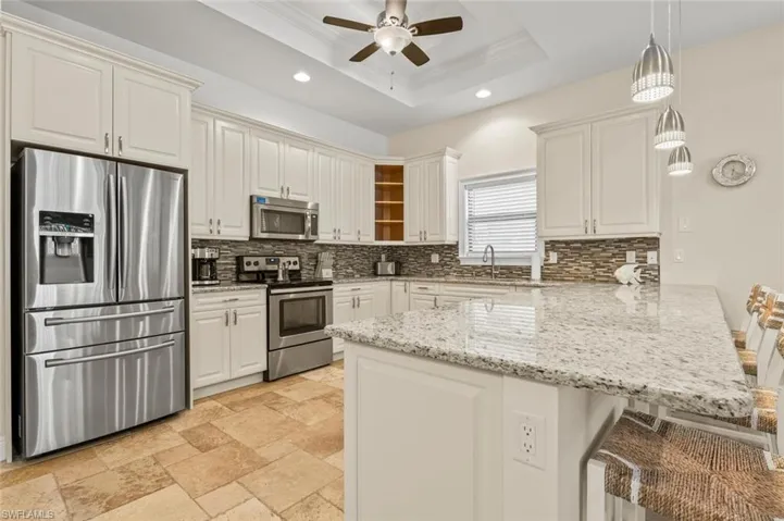 Kitchen with a peninsula, appliances with stainless steel finishes, ceiling fan, backsplash, and recessed lighting