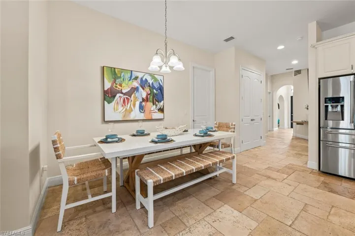 Dining space featuring arched walkways, stone tile flooring, a chandelier, and recessed lighting
