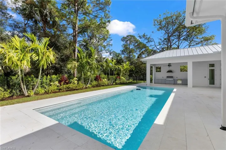 Large swimming pool with natural stone deck. Summer kitchen