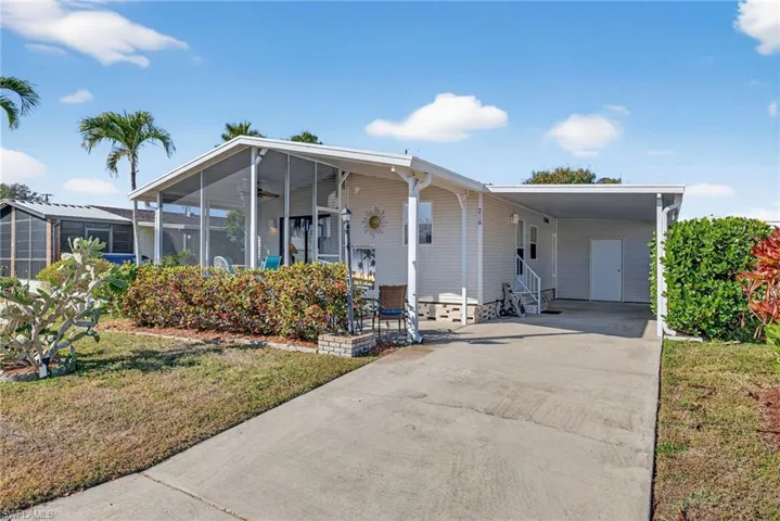 Manufactured / mobile home with driveway, a front yard, an attached carport, a sunroom, and a ceiling fan