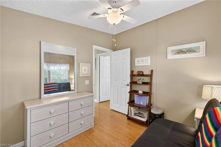 Living area featuring light wood-style floors, ceiling fan, and a textured ceiling