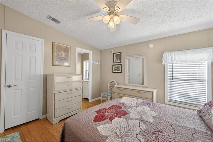 Bedroom featuring a textured ceiling, connected bathroom, a ceiling fan, and light wood finished floors