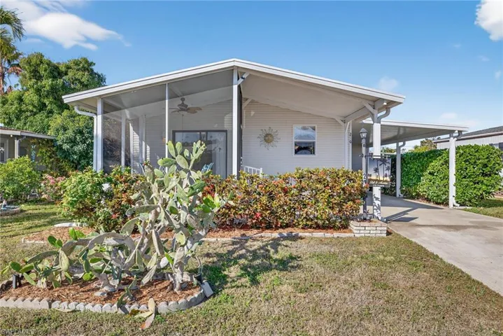 View of front of home with a carport, a ceiling fan, concrete driveway, and a front lawn