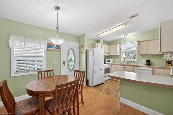 Kitchen with light countertops, white appliances, a textured ceiling, pendant lighting, and a peninsula