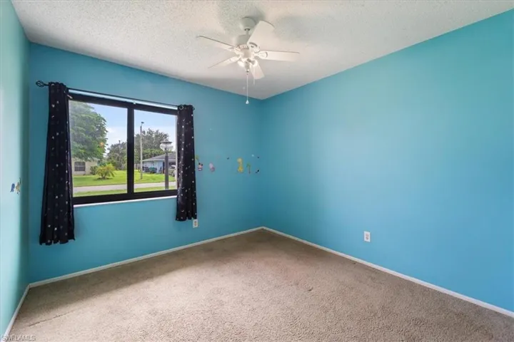Empty room with carpet flooring, a textured ceiling, and a ceiling fan