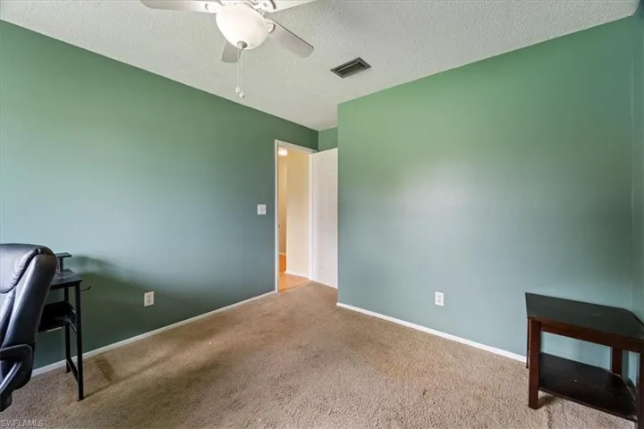 Home office with a textured ceiling, carpet floors, and a ceiling fan