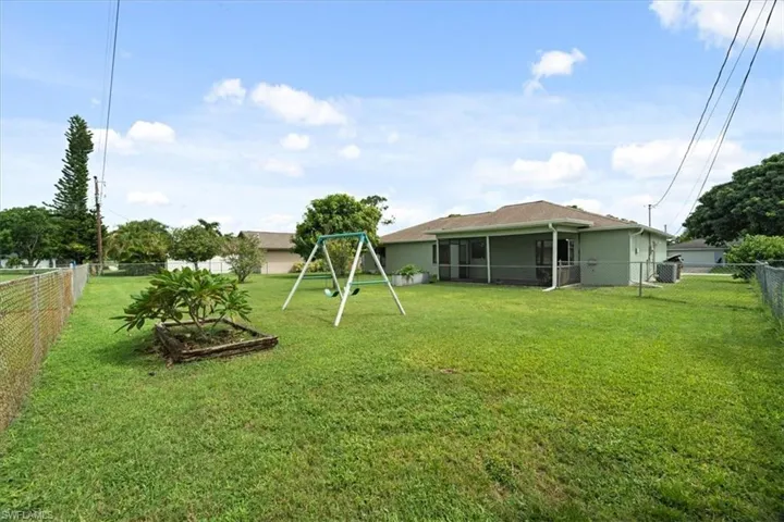 Fenced backyard featuring a playground and a sunroom