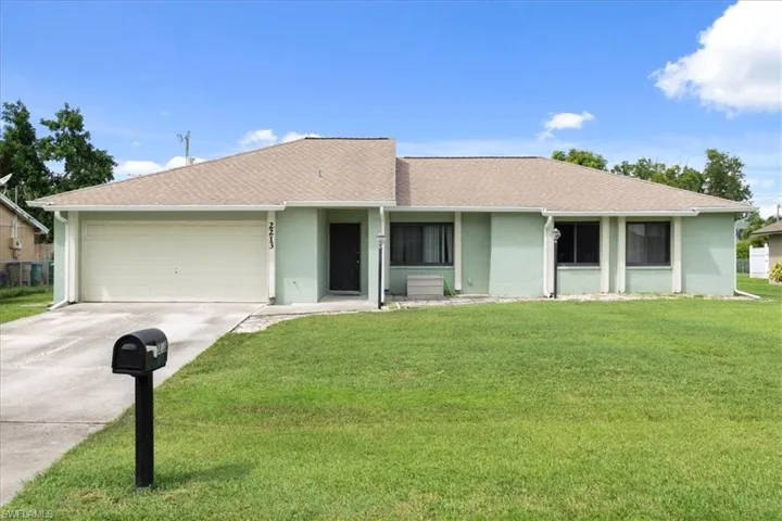 Ranch-style home with concrete driveway, stucco siding, roof with shingles, and a front yard