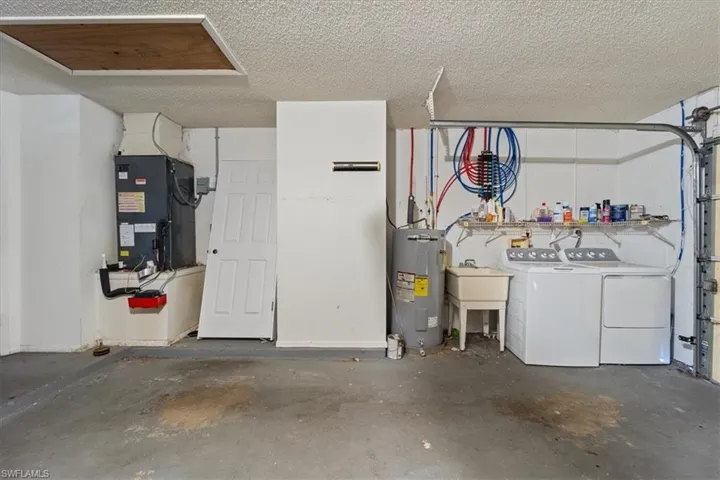 Garage featuring water heater, heating unit, and separate washer and dryer