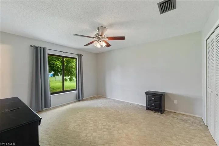Unfurnished bedroom featuring a textured ceiling, a closet, ceiling fan, and light carpet