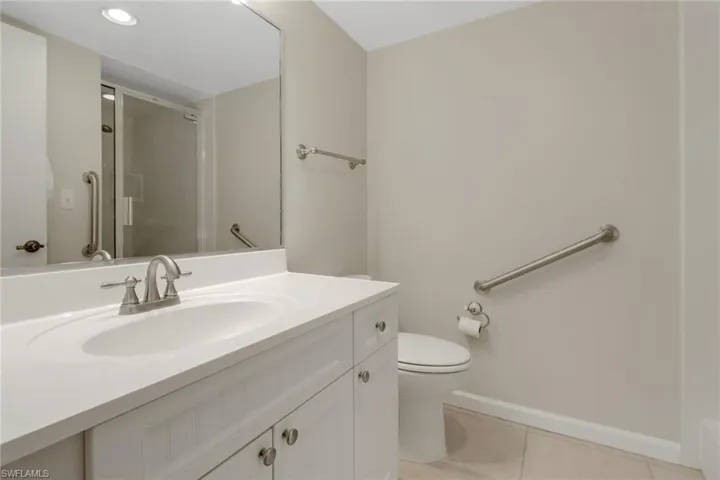 Bathroom with tile patterned flooring, toilet, vanity, baseboards, and an enclosed shower