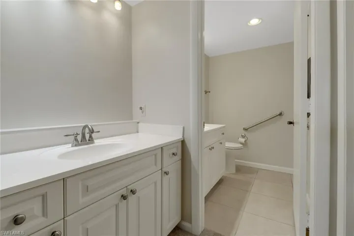 Bathroom with toilet, tile patterned floors, baseboards, and vanity