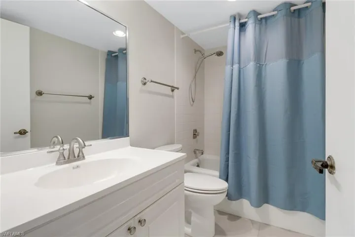 Full bathroom with tile patterned floors, shower / bathtub combination with curtain, toilet, and vanity