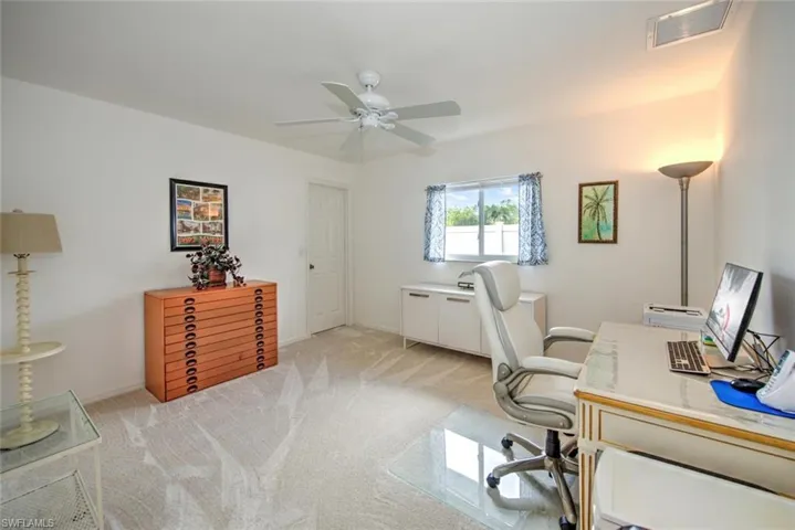 Home office with ceiling fan and light carpet