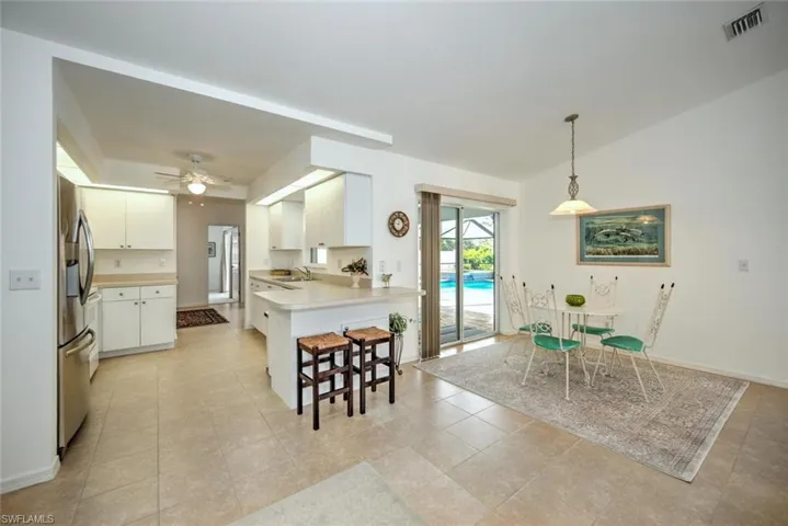 Kitchen featuring sink, white cabinetry, hanging light fixtures, stainless steel fridge, and kitchen peninsula
