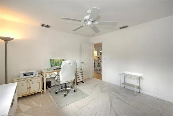 Carpeted office space featuring ceiling fan