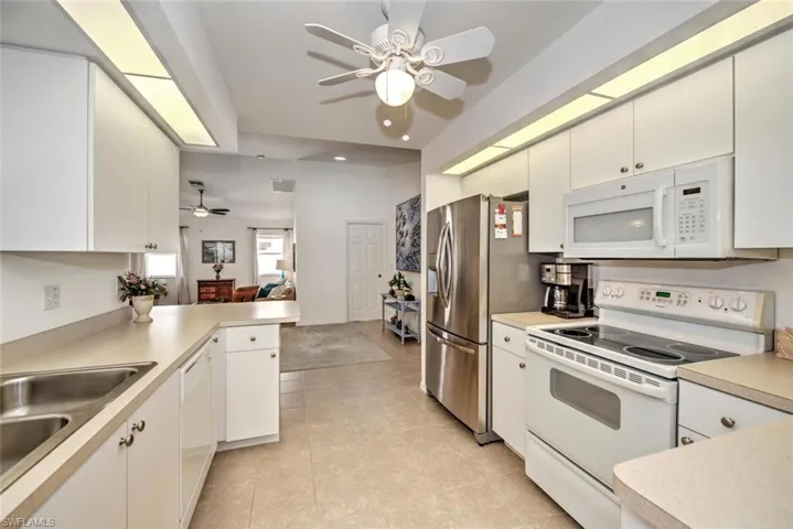 Kitchen featuring white cabinetry, white appliances, kitchen peninsula, and light tile patterned flooring