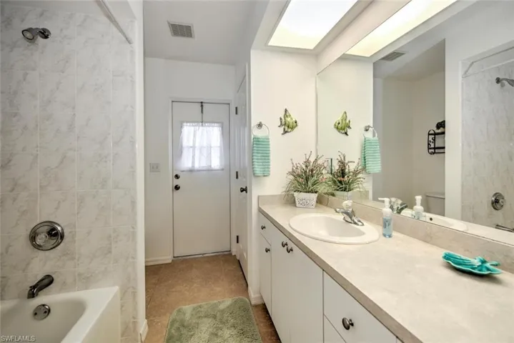Full bathroom featuring tiled shower / bath, a skylight, vanity, toilet, and tile patterned floors