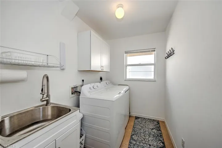 Laundry room featuring cabinets, separate washer and dryer, and sink