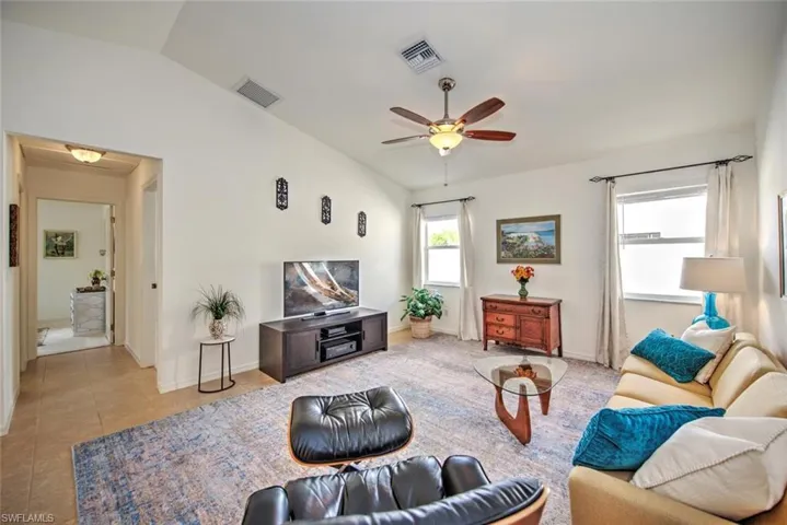 Living room featuring lofted ceiling, light tile patterned floors, and ceiling fan