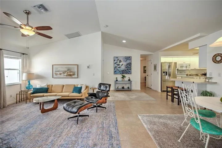 Living room featuring vaulted ceiling, ceiling fan, and light tile patterned flooring