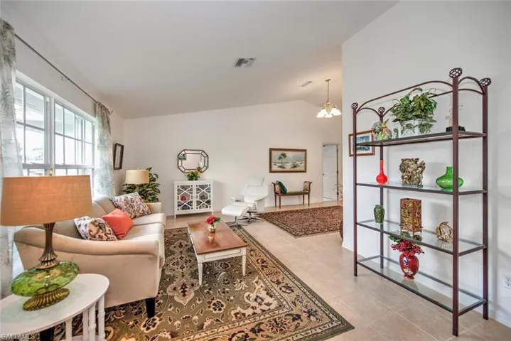 Tiled living room featuring lofted ceiling and a notable chandelier