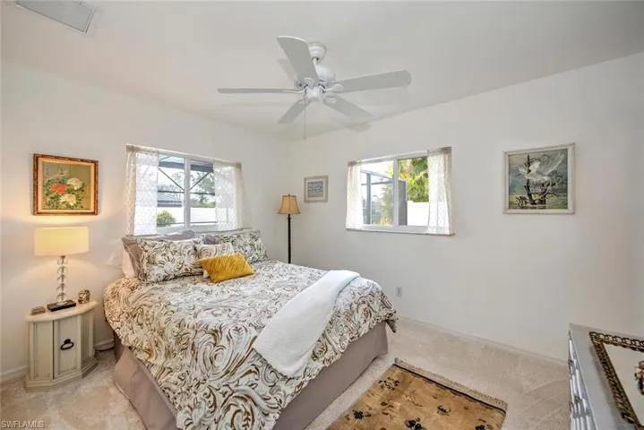 Carpeted bedroom featuring multiple windows and ceiling fan