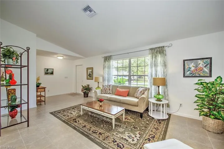 Tiled living room featuring vaulted ceiling
