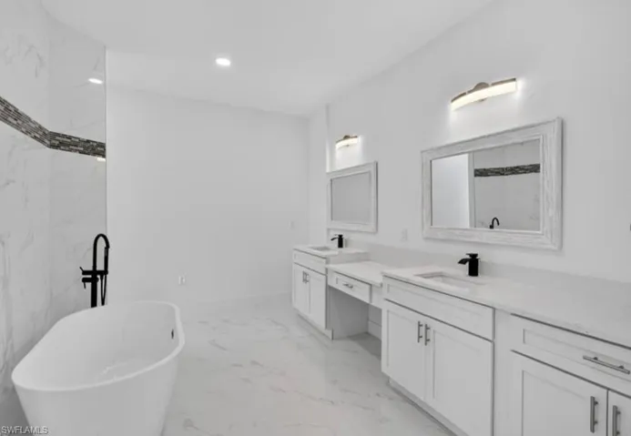Full bath with a freestanding tub, double vanity, light marble finish floors, recessed lighting, and a marble finish shower