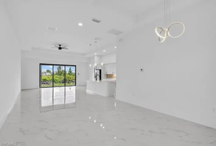 Unfurnished living room with a tray ceiling, light marble finish flooring, ceiling fan, and recessed lighting