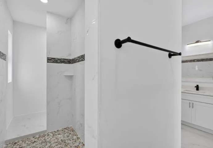 Full bathroom featuring light marble finish floors, a marble finish shower, vanity, and recessed lighting