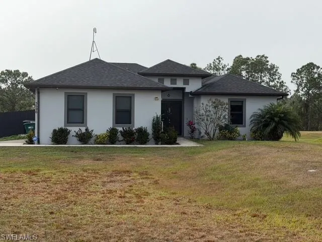 View of front of home with stucco siding and a shingled roof