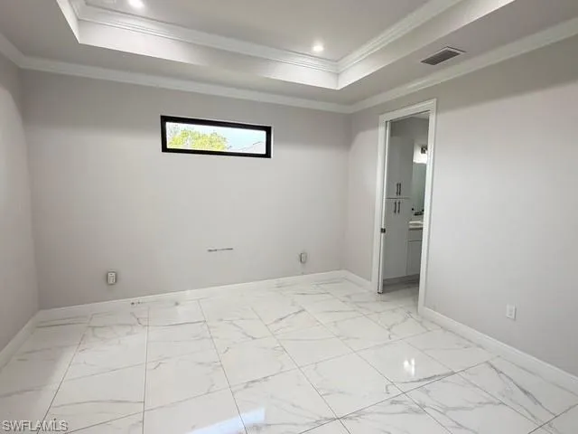 Principal room featuring light marble finish flooring, a raised ceiling, ornamental molding, and recessed lighting