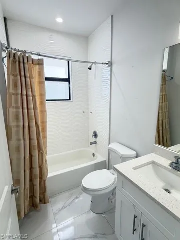 Full bath featuring shower / bathtub combination with curtain, vanity, and light marble finish floors