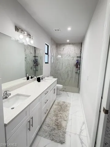 Principal Full bath featuring double vanity, a marble finish shower, and recessed lighting
