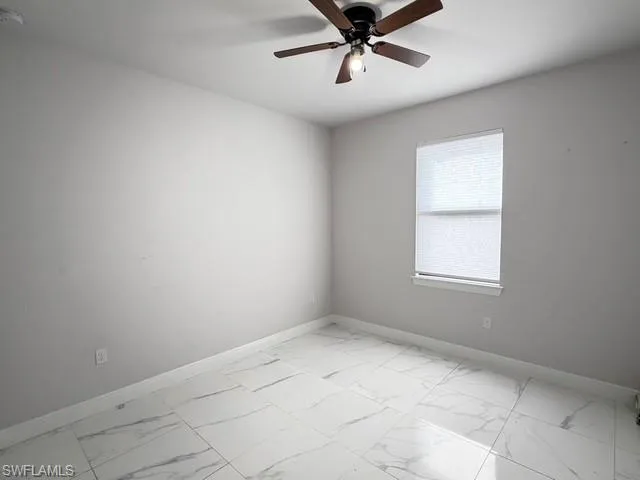Empty room with light marble finish floors and a smoke detector