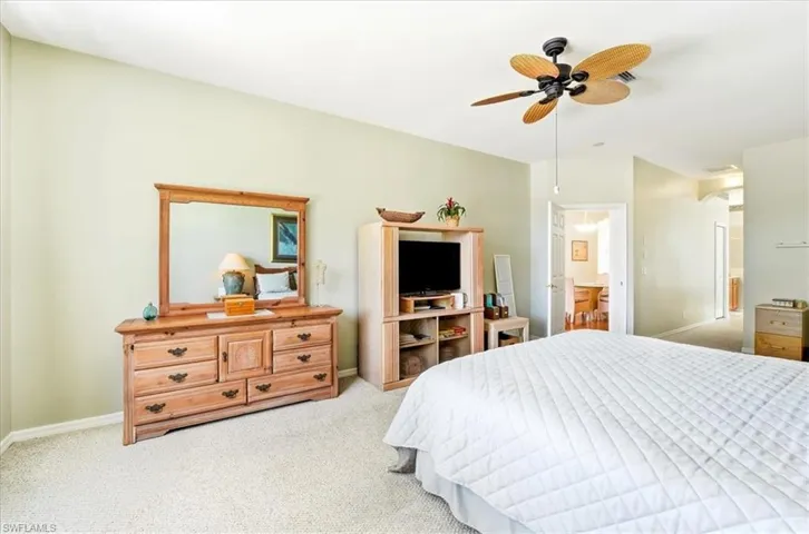 Carpeted bedroom with a ceiling fan and baseboards