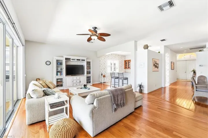 Living area featuring light wood-type flooring, ceiling fan, and arched walkways