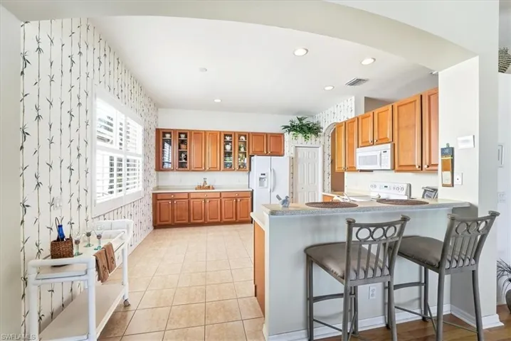 Kitchen with a kitchen breakfast bar, white appliances, recessed lighting, wood finish cabinets, and a peninsula