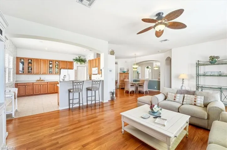 Living area featuring arched walkways, light wood-style floors, a ceiling fan, and recessed lighting