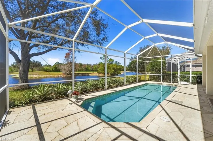 Swimming pool featuring a sunroom, a patio area, glass enclosure, and a water view