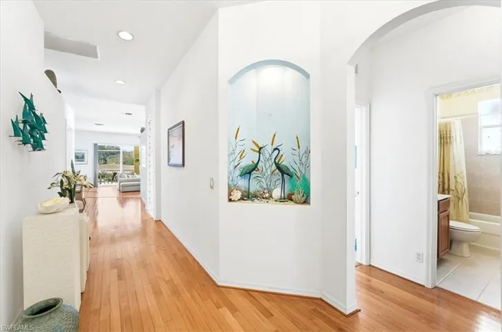 Hall with light wood finished floors and arched walkways