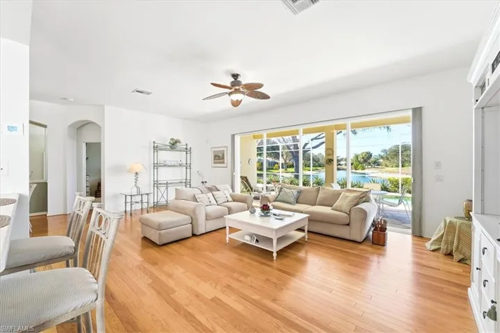 Living area with ceiling fan, light wood-style floors, and arched walkways