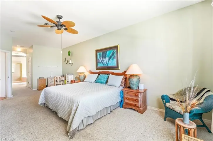 Carpeted bedroom featuring ensuite bathroom and a ceiling fan