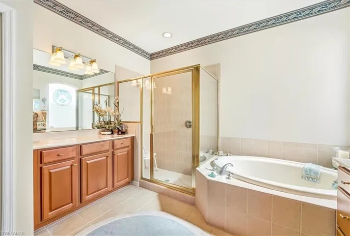 Full bathroom featuring vanity, a shower stall, a garden tub, and light tile patterned floors