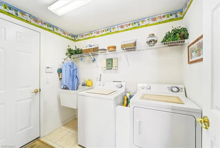 Laundry area with washing machine and clothes dryer and light tile patterned flooring