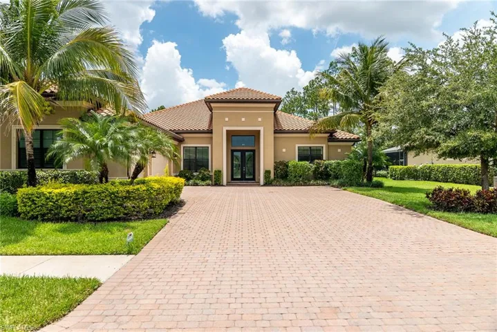 Mediterranean / spanish house with a tile roof, driveway, stucco siding, and french doors