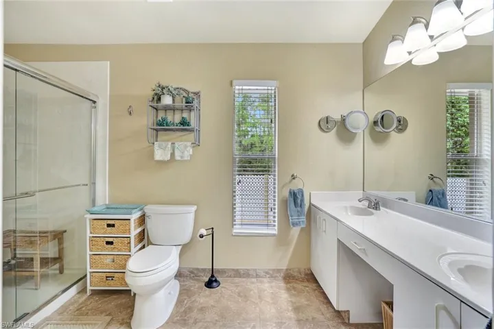 Bathroom featuring double vanity, a stall shower, and healthy amount of natural light