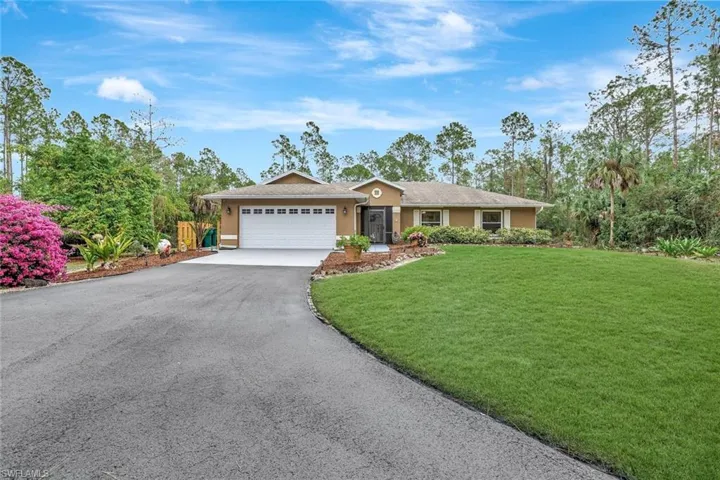 Single story home with asphalt driveway, stucco siding, a front lawn, and a garage